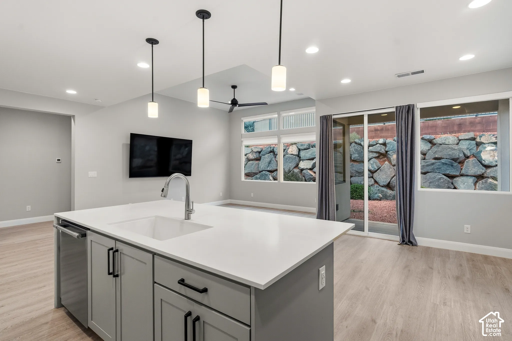 Center island featuring a white countertop, undermount sink, and grey cabinetry with matte black hardware