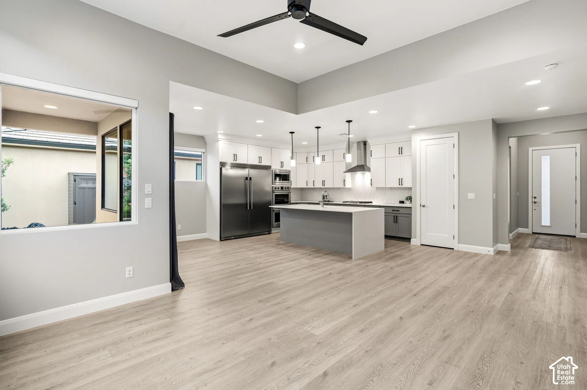 Open-concept kitchen featuring two-tone cabinetry, a central island, recessed lighting, stainless steel appliances, and wood-finish flooring
