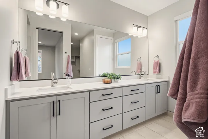 Dual-sink vanity with light-gray cabinetry, solid-surface countertop, matte black hardware, and an expansive wall-to-wall mirror