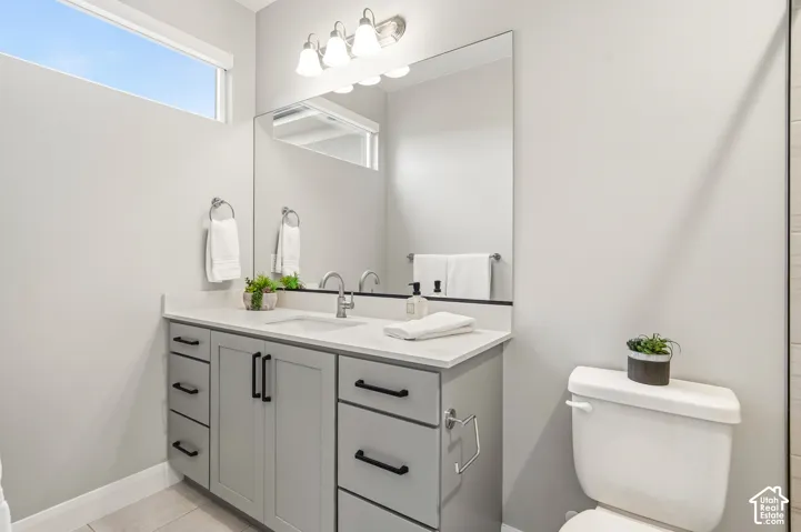 Shaker-style vanity featuring a light-toned countertop, undermount sink, matte black hardware, large frameless mirror, and transom window
