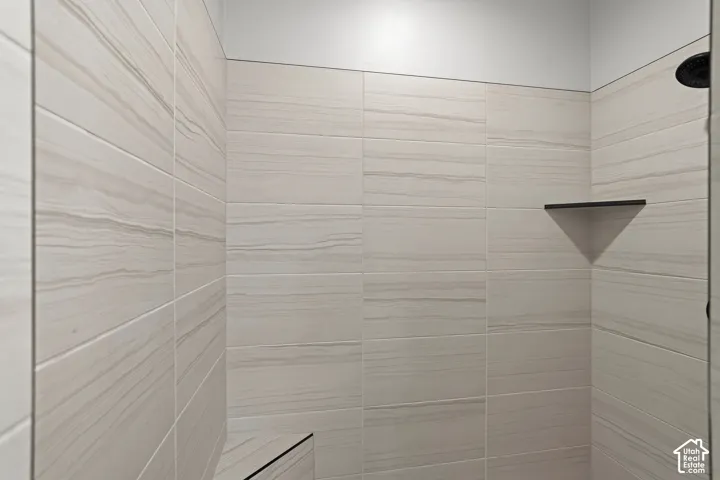 Shower featuring floor-to-ceiling horizontal tile, built-in corner tile bench, integrated corner shelving, and matte black plumbing fixtures