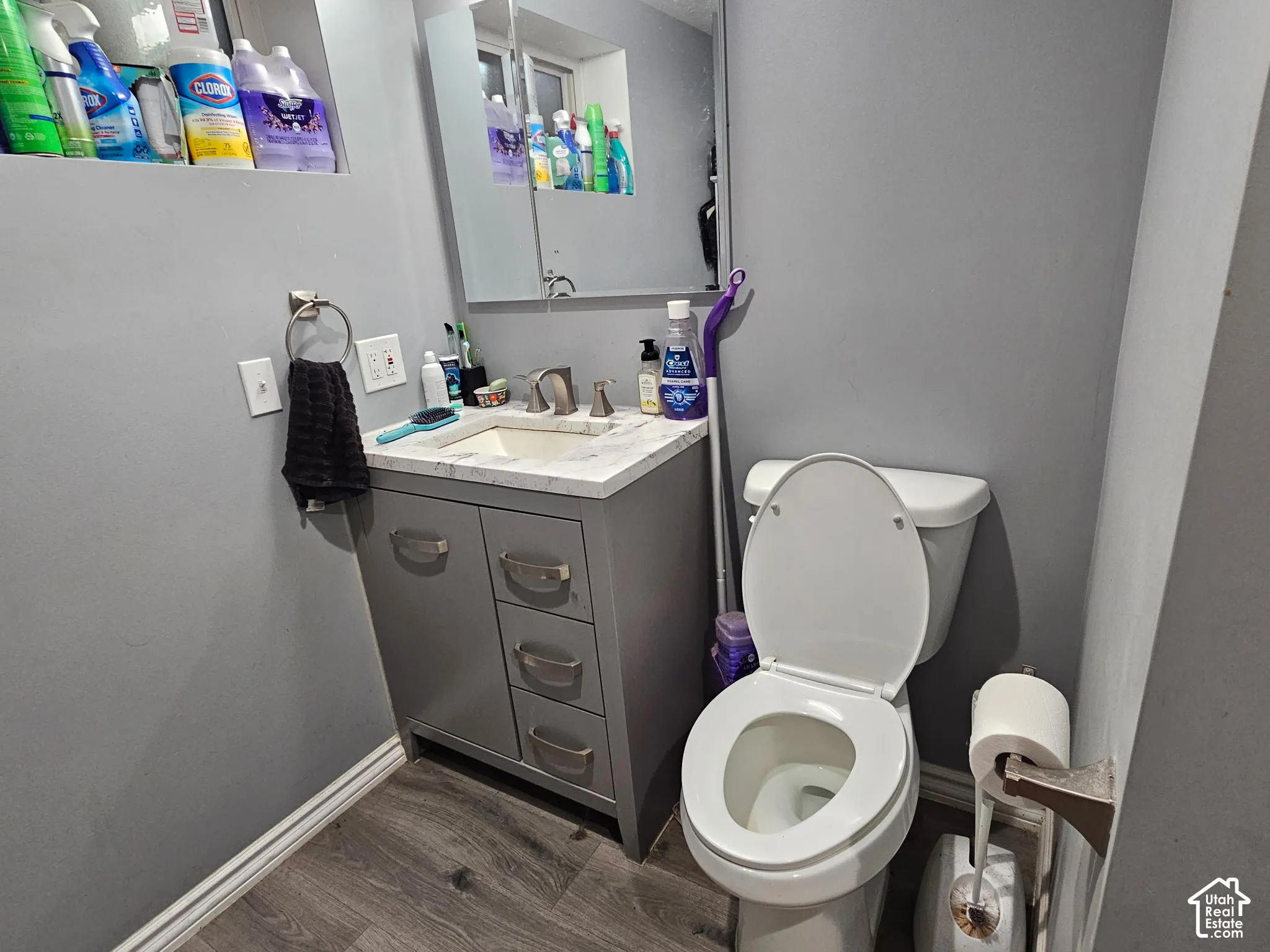 Vanity featuring a stone-composite countertop, undermount sink, metallic hardware, and wood-finish flooring