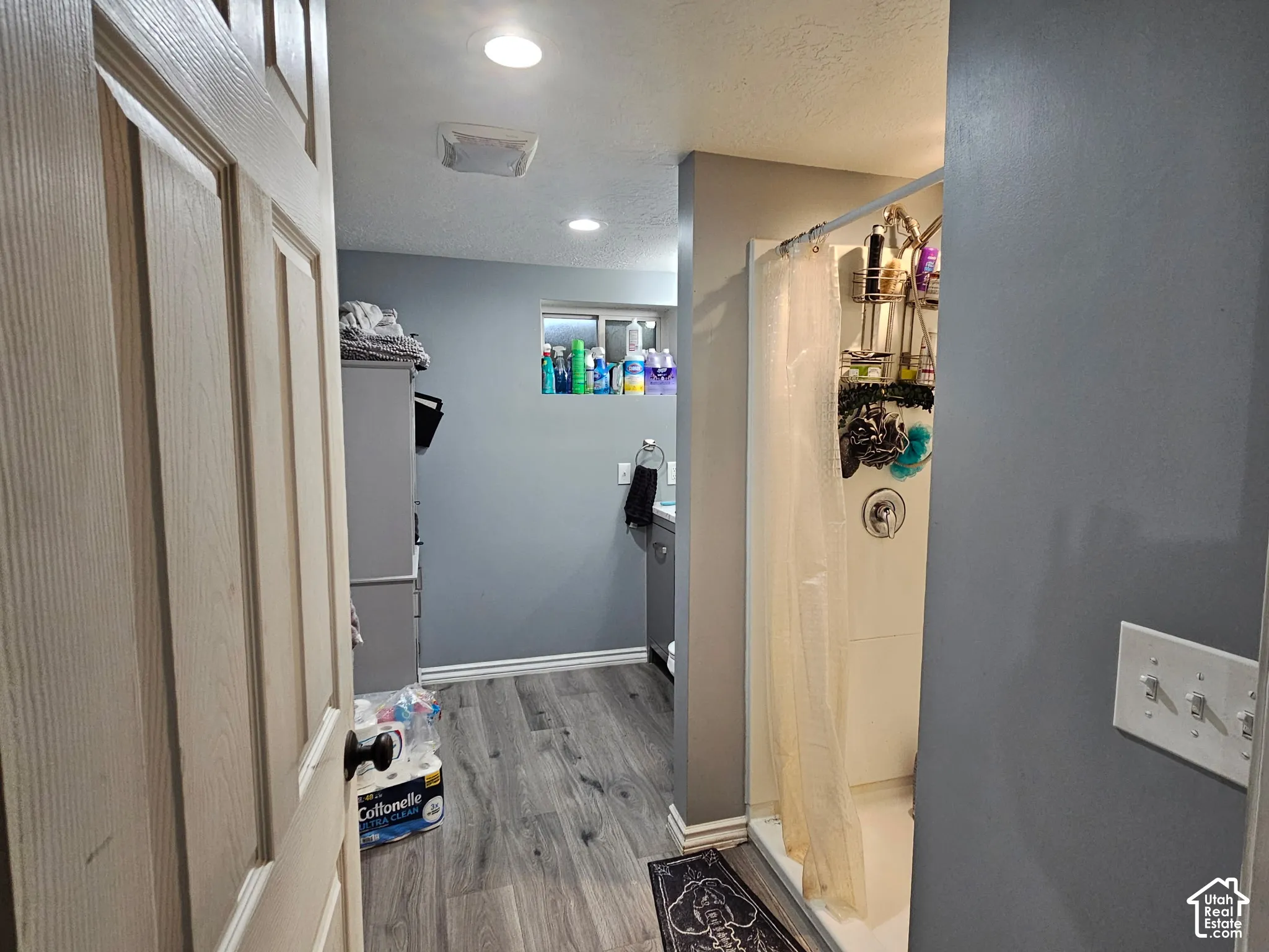 Bathroom featuring wood-finish flooring, recessed lighting, and a walk-in shower with a surround