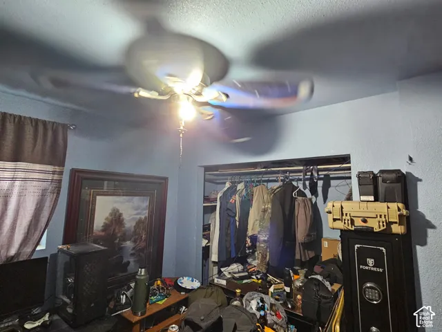 Ceiling-mounted fan with integrated light fixture and interior closet featuring a built-in shelving unit
