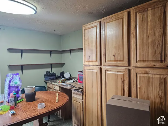 Full-height wood cabinetry with raised-panel doors, solid surface countertops, and wall-mounted wooden shelving
