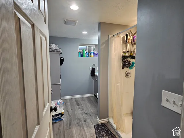Bathroom featuring wood-finish flooring, recessed lighting, and a walk-in shower with a surround