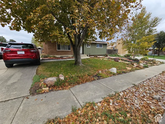 Exterior facade featuring a combination of brick masonry and vertical siding, concrete driveway, and front landscaping with rock garden elements