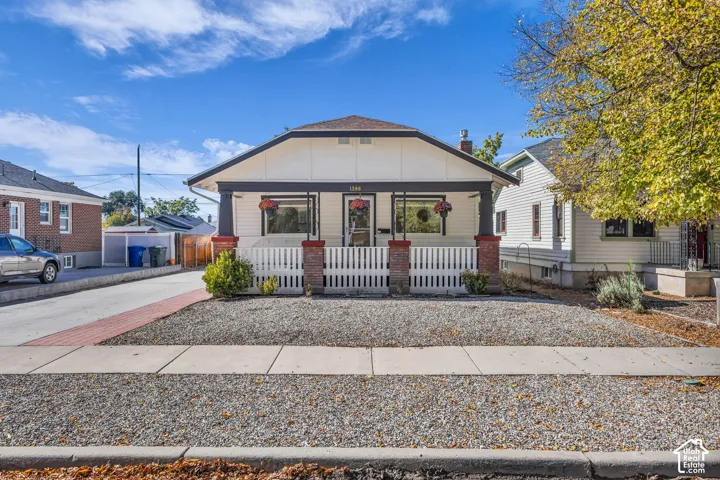Bungalow exterior featuring a covered front porch with tapered columns, brick masonry piers, and a white wood-slat railing