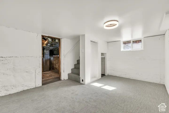 Finished lower-level room featuring wall-to-wall carpeting, painted masonry walls, recessed ceiling lighting, and a window