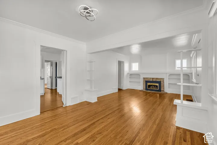 Interior space featuring wood-finish flooring, a fireplace with a stone-surround hearth, built-in shelving, and a modern circular ceiling fixture