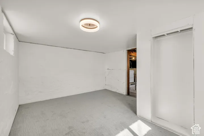 Room featuring neutral-toned carpeting, white masonry walls, and a circular LED flush-mount ceiling light fixture