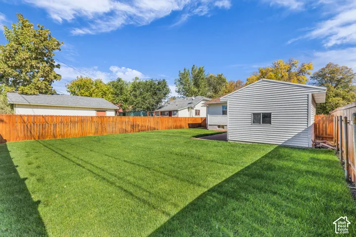 Backyard featuring a manicured lawn, wood fencing, and a detached structure with white siding