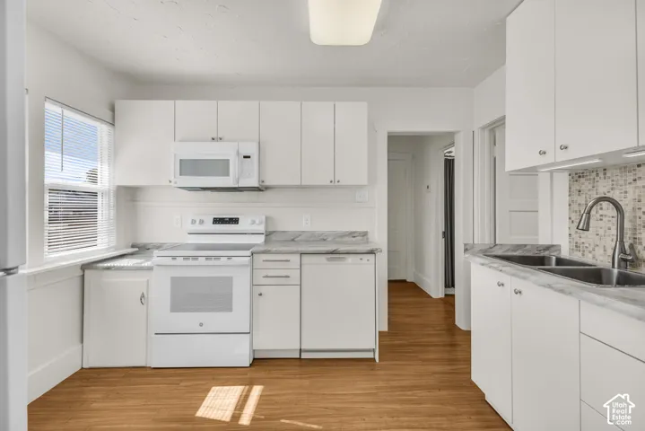 Kitchen featuring white cabinetry, stone-finish countertops, wood-finish flooring, mosaic tile backsplash, and a dual-basin stainless steel sink