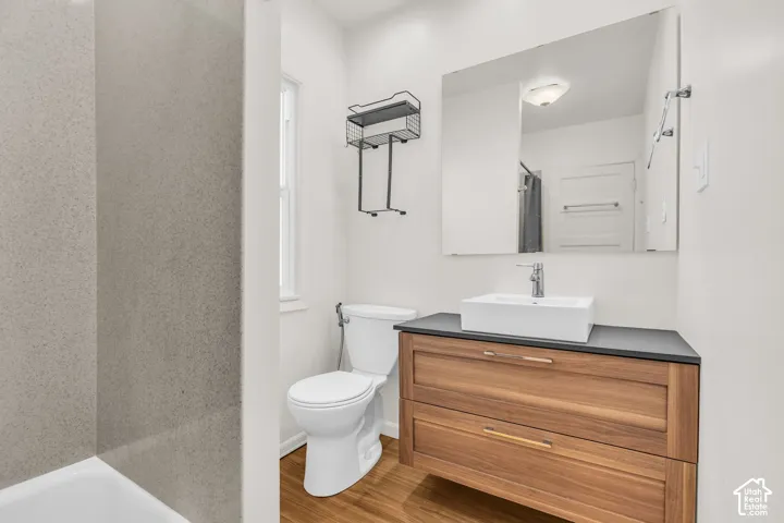 Floating wood-finish vanity with a rectangular vessel sink, solid-surface countertop, full-width mirror, and matte-finish wall-mounted shelving