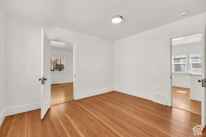 Interior room featuring wood-finish flooring, white walls, two interior door frames, and a flush-mount ceiling light fixture