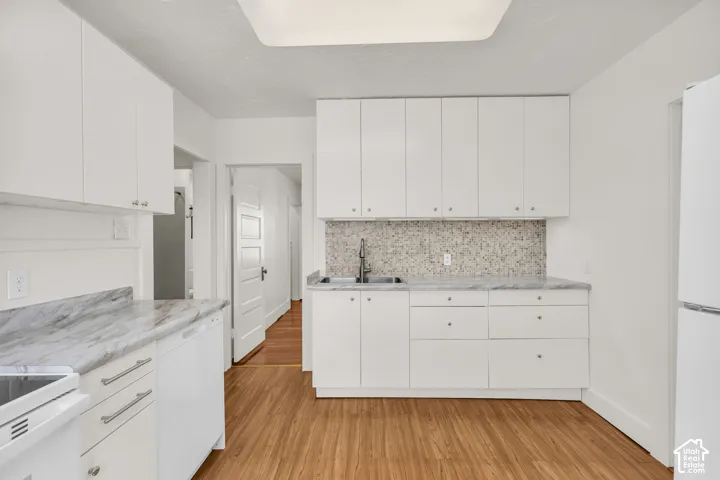 Kitchen featuring white cabinetry, stone-finish countertops, tile backsplash, wood-finish flooring, and a stainless steel double-basin sink