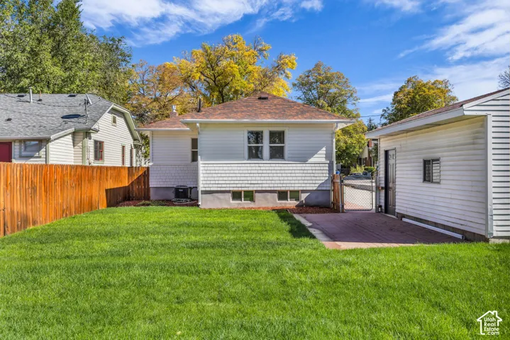 Fenced backyard featuring a manicured lawn, paved patio area, wood privacy fencing, and exterior shingle siding