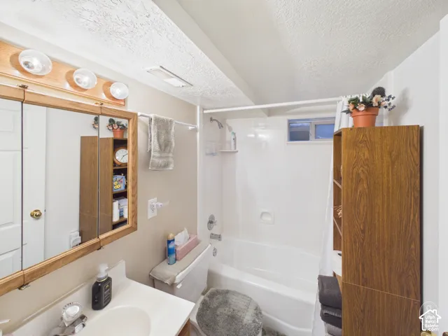 Bathroom featuring a molded acrylic tub and shower surround, wall-mounted medicine cabinet with a wood-finish frame, and integrated vanity countertop with a sink