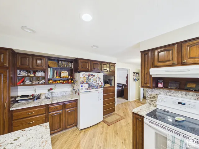 Kitchen featuring stained wood cabinetry, stone-finish countertops, recessed ceiling lighting, and wood-finish flooring