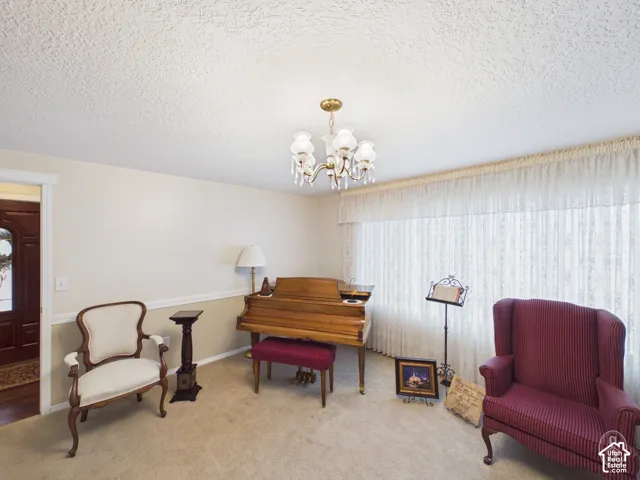 Interior space featuring a brass multi-arm chandelier, large floor-to-ceiling drapery, chair rail molding, and a solid wood door with decorative glass paneling