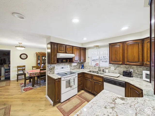 Kitchen featuring dark wood cabinetry, light-toned stone-finish countertops, recessed lighting, and wood-finish flooring