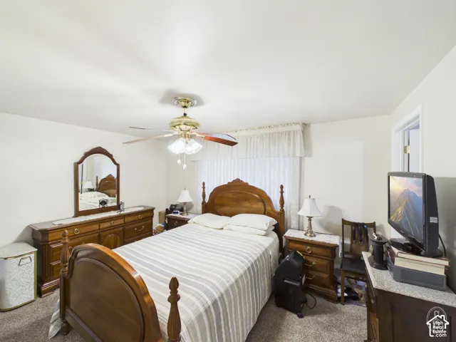 Room featuring neutral wall tones, textured carpeting, and a multi-blade ceiling fan with integrated light fixture