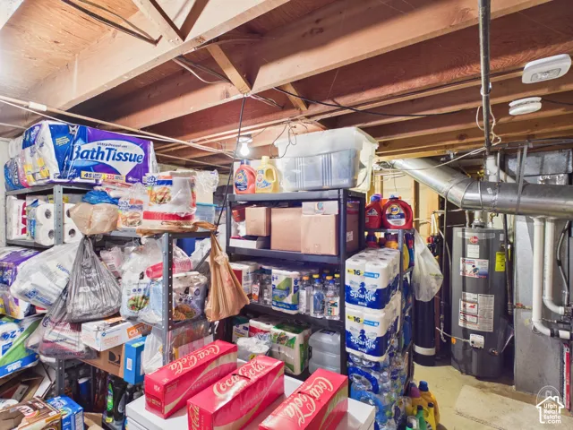Unfinished storage area featuring exposed wood ceiling joists and a tall-profile water heater