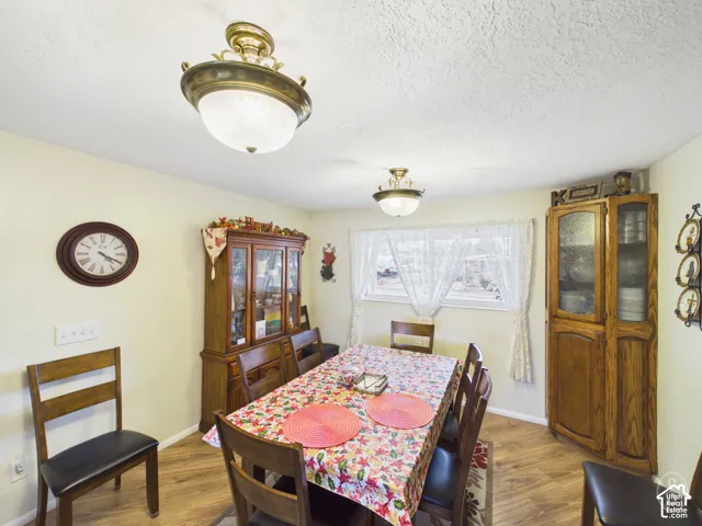 Dining area featuring wood-finish flooring, two decorative brass-tone semi-flush mount light fixtures, and a corner-installed built-in cabinetry unit
