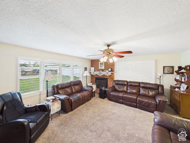 Brick fireplace with a decorative mantel, plantation shutters, and ceiling fan