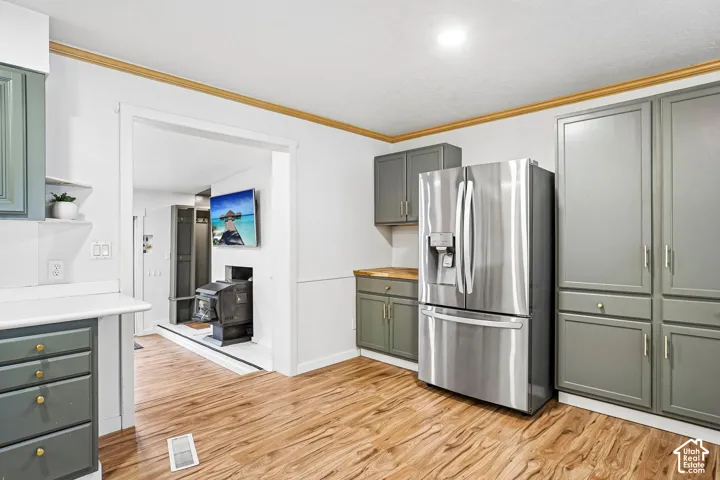 Kitchen featuring olive-toned cabinetry, stainless steel French-door refrigerator, wood-finish flooring, and crown molding