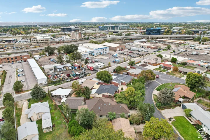 Aerial perspective of residential property featuring a multi-pitched shingle roof and mature trees on a corner lot