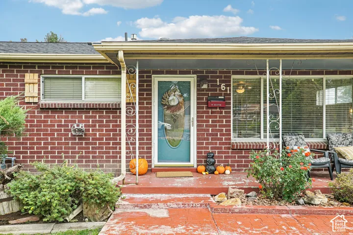 Red brick exterior featuring a covered front porch with decorative iron columns, a glass-panel storm door, and horizontal sliding windows