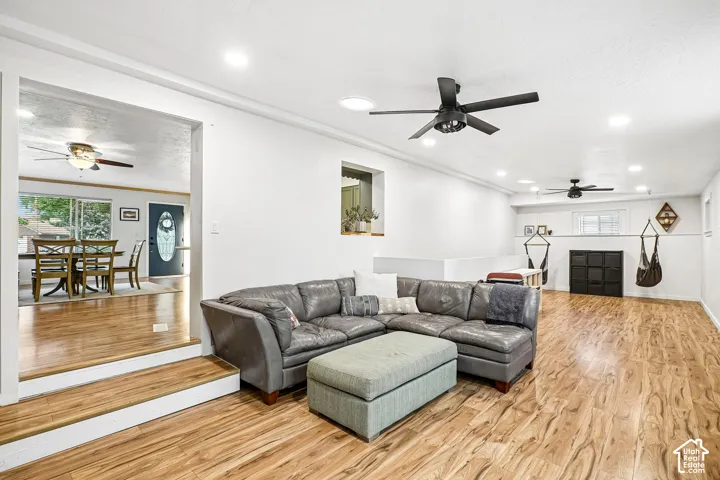 Wood-finish flooring, recessed lighting, matte black ceiling fans, and a multi-level floor plan with wide openings