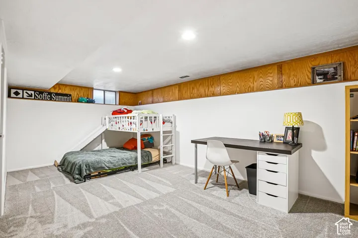 Neutral-toned wall-to-wall carpeting, recessed ceiling lighting, and wood-paneled wall accents