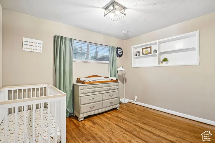 Room featuring wood-finish flooring, built-in recessed shelving, sliding window, and geometric flush-mount ceiling lighting