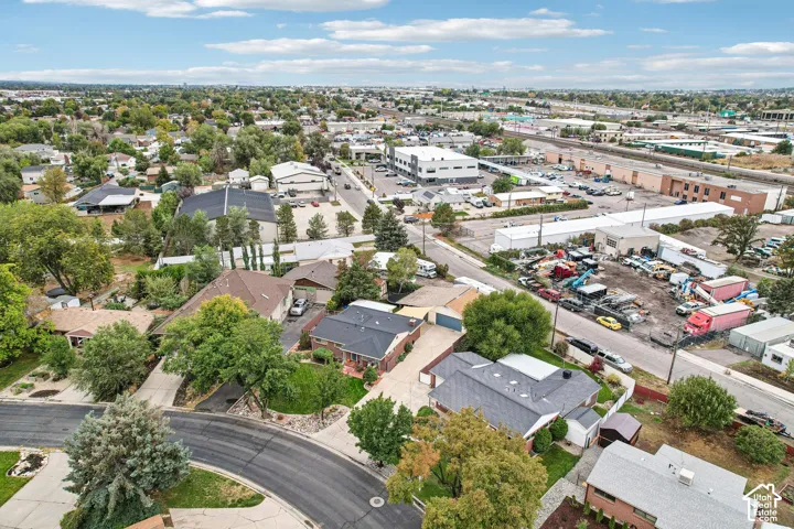 Aerial perspective of a suburban neighborhood featuring paved streets, mature trees, manicured residential lawns, and residential structures with various roof lines
