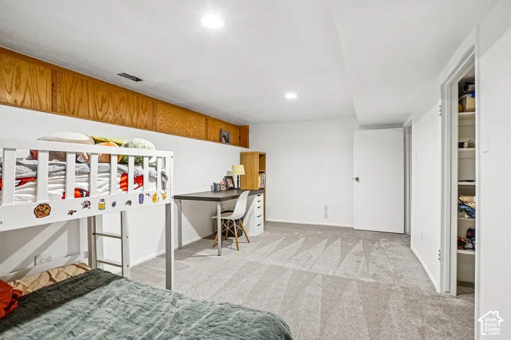 Neutral-toned carpeting, built-in wooden storage cabinetry, recessed lighting, and a walk-in closet with integrated shelving