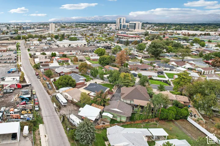 Aerial perspective featuring a suburban residential setting, mature trees, and a mountain range backdrop