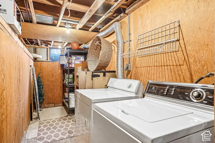 Utility area featuring plywood wall paneling, exposed ceiling joists, and a wall-mounted wire storage rack