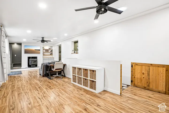 Wood-finish flooring, matte black ceiling fans, recessed lighting, wood-paneled gate, and built-in shelving with integrated lighting