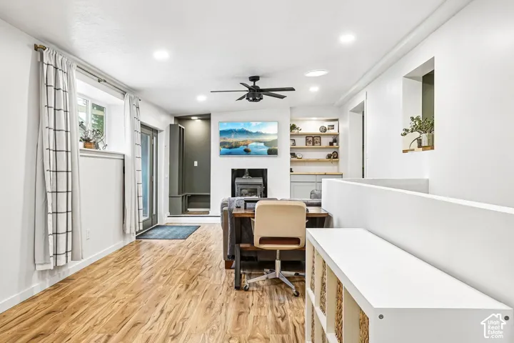 Wood-finish flooring, recessed lighting, ceiling fan, wood-burning stove with mantel, and built-in shelving