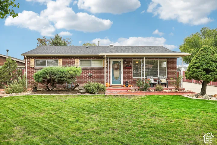 Single-story brick exterior featuring a covered front porch, asphalt shingle roof, and expansive front lawn with mature landscaping