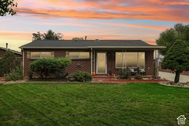 Single-story brick exterior featuring a covered front porch, low-pitch roofline, and manicured front lawn