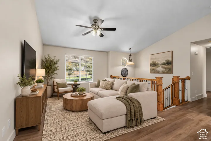 Living area featuring a vaulted ceiling, wood-finish flooring, and a ceiling fan with integrated lighting