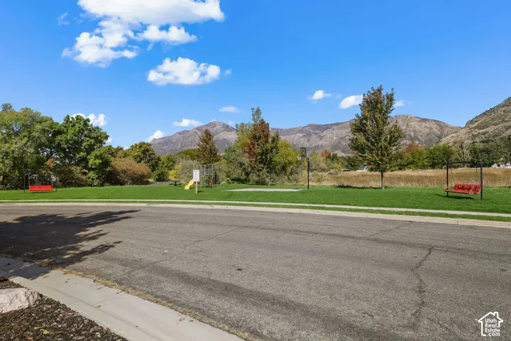 Expansive grassy common area featuring mature trees and mountain scenery