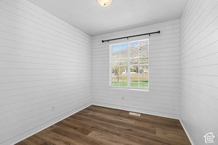 Interior room featuring horizontal white shiplap walls, wood-finish flooring, and a window with exterior mountain scenery