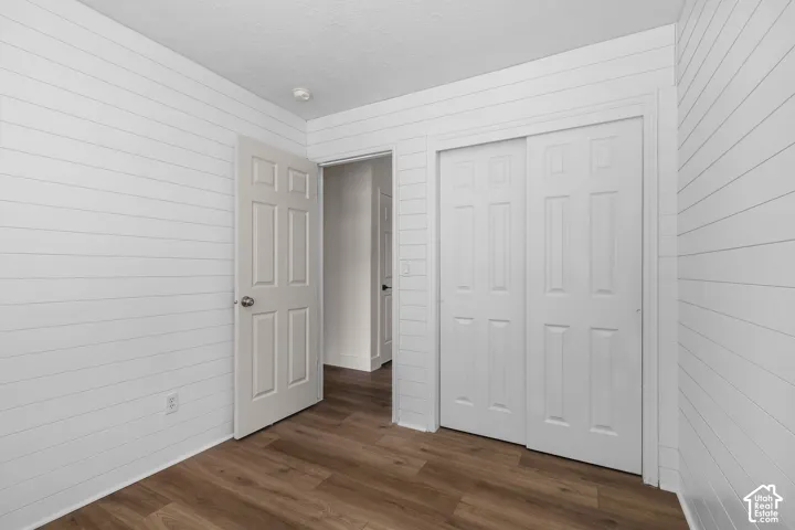 Room featuring white horizontal plank wall detailing, wood-finish flooring, a six-panel swing door, and a six-panel sliding closet door