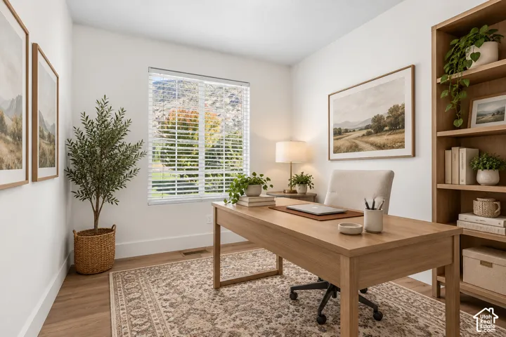 Neutral-toned office featuring wood-finish flooring, a built-in wood shelving unit, and a window with mountain scenery