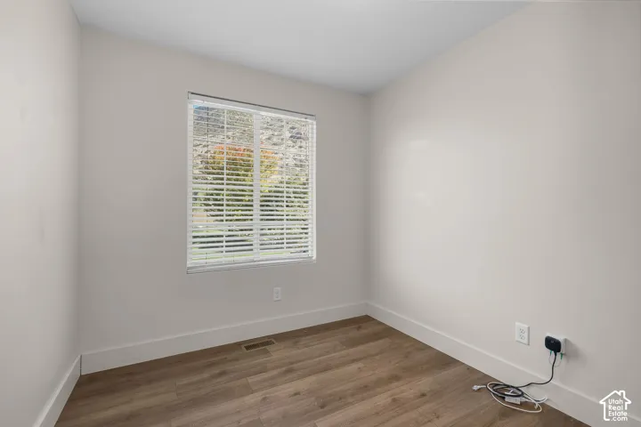 Neutral-toned walls, wood-finish flooring, and horizontal window blinds with a mountain backdrop