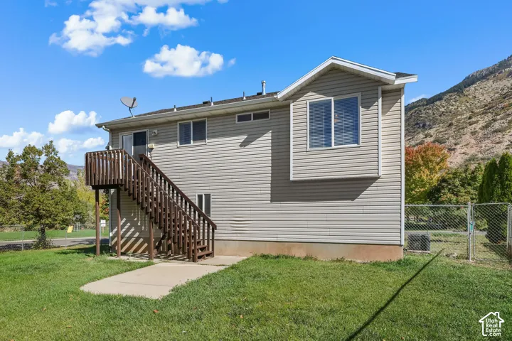 Exterior featuring horizontal siding, elevated wood deck with stairs, concrete ground-level pad, and mountain backdrop
